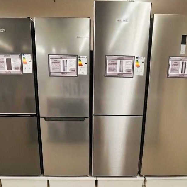 Kühlschränke Vier silberne Kühlschränke nebeneinander in einem Geschäft, mit Preisschildern.